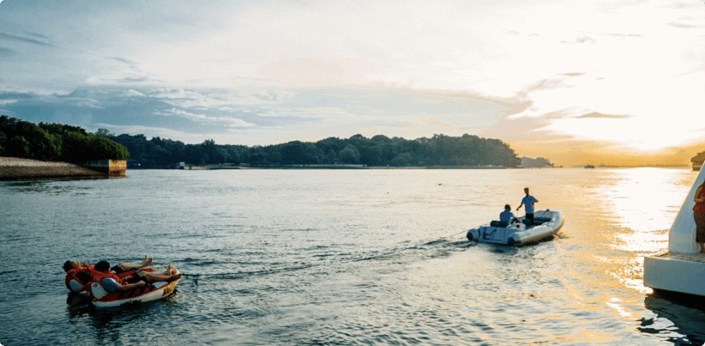 A motorboat pulling 2 boats with 2 people on them