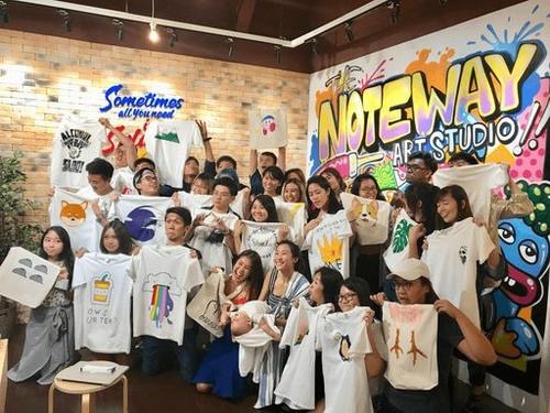A group of people posing with their painted tees, a team-building event